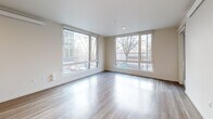 Located at 16180 NE 80th St in Redmond, WA, this well-designed 2-bedroom, 1-bathroom residence offers a thoughtful layout across a single floor. The open-concept kitchen and living area serves as the heart of the home, featuring light wood-style flooring, large corner windows that flood the space with natural light, and views of the surrounding neighborhood. The modern kitchen is equipped with stainless steel appliances including a refrigerator, range, and microwave, complemented by sleek white cabinetry, stone countertops, and a functional island with a sink. A dedicated pantry provides additional storage. The living area opens to a private balcony through a glass door, extending the living space outdoors. In-unit stacked laundry is conveniently tucked within its own closet. The two bedrooms feature plush carpeting, and the primary bedroom includes a spacious walk-in closet with wire shelving systems. The second bedroom benefits from a large window with neighborhood views. The full bathroom is finished with wood-look tile flooring, a single vanity with stone countertops, and a soaking tub with shower. A hallway connects all rooms efficiently, completing this clean, contemporary residence.