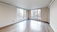 Located at 16180 NE 80th St in Redmond, WA, this well-designed 2-bedroom, 1-bathroom residence offers a thoughtful layout across a single floor. The open-concept kitchen and living area serves as the heart of the home, featuring light wood-style flooring, large corner windows that flood the space with natural light, and views of the surrounding neighborhood. The modern kitchen is equipped with stainless steel appliances including a refrigerator, range, and microwave, complemented by sleek white cabinetry, stone countertops, and a functional island with a sink. A dedicated pantry provides additional storage. The living area opens to a private balcony through a glass door, extending the living space outdoors. In-unit stacked laundry is conveniently tucked within its own closet. The two bedrooms feature plush carpeting, and the primary bedroom includes a spacious walk-in closet with wire shelving systems. The second bedroom benefits from a large window with neighborhood views. The full bathroom is finished with wood-look tile flooring, a single vanity with stone countertops, and a soaking tub with shower. A hallway connects all rooms efficiently, completing this clean, contemporary residence.