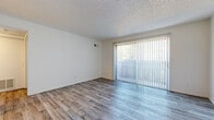 Located at 6602 E Harry St in Wichita, Kansas, this single-floor unit offers a clean, functional layout with a neutral color palette and a variety of updated finishes throughout. The living area is bright and open, featuring wood-look plank flooring in a cool gray tone and a textured ceiling. A large sliding glass door fitted with vertical blinds fills the space with natural light and provides direct access to a private outdoor patio, offering views of the surrounding greenery. The kitchen is designed with practicality in mind, featuring a pass-through counter with marble-style laminate surfaces, white cabinetry, and full-size appliances including a refrigerator and range. The open sightlines between the kitchen and living area enhance the sense of space and connectivity. The bedrooms are comfortably sized, with warm-toned carpet flooring and ceiling fans for added comfort. Additional rooms feature the same light wood-look flooring, maintaining a cohesive aesthetic throughout. The bathroom is well-appointed with a tiled tub-and-shower combo, wood-look flooring, a marble-style vanity countertop, and brushed nickel hardware accents. The textured ceilings are consistent throughout, lending a classic residential character to the unit.