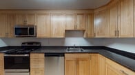 Located at 62 Waterfall Drive in Canton, Massachusetts, this single-floor residence offers a well-organized layout with clearly defined living spaces. The kitchen is a functional centerpiece, showcasing light maple shaker-style cabinetry extending to the ceiling, dark speckled countertops, and stainless steel appliances including a dishwasher, range, and over-the-range microwave. Light tile flooring completes the clean, practical design.

The living and dining areas flow naturally from one another, with warm neutral carpet and a connecting hallway leading to the private quarters. The corridor layout provides clear separation between communal and bedroom spaces. Bedrooms are carpeted and finished with neutral tones, with multiple windows framing views of surrounding greenery. One bedroom features a vaulted ceiling detail, adding architectural interest, while another includes a built-in closet with shelving and rail storage.

Two bathrooms serve the residence: one full bath with a tub-shower combination, white cabinetry, and tile flooring, and a second featuring a corner neo-angle glass shower enclosure alongside a vanity with medicine cabinet. Both bathrooms maintain a clean, white aesthetic throughout.