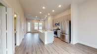 This single-story space showcases a contemporary design with a thoughtfully planned open-concept layout. The kitchen serves as the heart of the unit, centered around a white waterfall island with an integrated sink. Gray shaker-style cabinetry lines the walls, complemented by a full suite of stainless steel appliances including a gas range, microwave, and French door refrigerator. Recessed lighting illuminates the space, which flows seamlessly into the living area. Light-toned luxury vinyl plank flooring extends throughout the main living spaces, adding warmth and visual continuity.

The living area benefits from generous natural light, courtesy of multiple windows and a glass-panel exterior door. A ceiling fan provides additional comfort overhead. Bedrooms feature plush carpet flooring, ceiling fans, and windows that allow ample natural light to filter in.

The bathrooms are finished with striking marble-style tile covering both the floors and walls. The primary bathroom includes a walk-in glass-enclosed shower and a gray vanity with gold-tone hardware, while a secondary bathroom features a tiled tub-shower combination with matching finishes throughout.