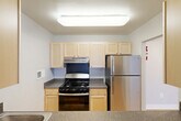 This well-appointed one-bedroom, two-bathroom residence at 601 Four Mile Rd in Alexandria, Virginia offers a thoughtfully designed single-level layout. Throughout the living areas and bedroom, warm honey-toned hardwood-style flooring creates a cohesive and inviting atmosphere, complemented by soft gray walls and clean white baseboards.

The open living area is generously sized, featuring a ceiling fan with light fixture and direct sightlines into the kitchen, creating a connected and functional flow. The kitchen is equipped with light maple cabinetry, granite-style countertops, a gas range, and a stainless steel refrigerator, offering ample workspace and storage. A wide countertop peninsula separates the kitchen from the living space.

The spacious primary bedroom features a window overlooking greenery, providing natural light and outdoor views. It boasts dual built-in closets with bifold doors, offering exceptional storage. A ceiling-mounted fan adds comfort to the room.

Both bathrooms are well-appointed, with one featuring a vanity with light maple cabinetry, a white countertop, and a large mirrored medicine cabinet. The bathtub surround is tiled in large-format marble-look tile, lending an elegant, modern aesthetic to the space.