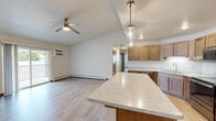 Located at 2200 Nicolet Dr in Green Bay, Wisconsin, this single-floor, 2-bedroom, 2-bathroom residence offers a thoughtfully designed open-concept layout. The combined kitchen and living area serves as the heart of the home, featuring light hardwood-style flooring, a ceiling fan, and a wall-mounted A/C unit. The kitchen is well-equipped with warm-toned wood cabinetry, light marble-patterned countertops, stainless steel appliances including a range and refrigerator, a double sink, and a central island with pendant lighting overhead — ideal for both meal preparation and casual dining.

The two bedrooms are finished with plush carpeting and ceiling fans, each benefiting from natural light through windows with blinds and baseboard heating. The spacious primary bedroom includes a walk-in closet outfitted with built-in shelving and hanging rods for ample storage.

The two bathrooms are clean and functional: one features a full soaking tub with a shower combination and a vanity with a marble-style countertop, while the second offers a standalone walk-in shower with chrome fixtures. Both bathrooms are finished with light hardwood-style flooring. Hallway areas connect the spaces efficiently, completing this practical and comfortable single-level home.