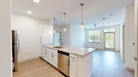 Located at 11750 Alliance Cir in Chester, VA, this well-designed single-floor residence offers three bedrooms, two bathrooms, and two closets across a thoughtfully arranged floor plan. The open-concept kitchen and living area serves as the centerpiece of the home, highlighted by a large granite-topped island with an undermount sink, elegant pendant lighting with brass fixtures, and crisp white shaker cabinetry. The kitchen is fully equipped with stainless steel appliances, including a range, microwave, refrigerator, and dishwasher, complemented by a light subway tile backsplash. Light wood-tone flooring runs throughout the main living areas, lending warmth and continuity to the space. The living room benefits from abundant natural light through large windows and a glass door that opens to an outdoor balcony, complete with a ceiling fan overhead. The bedrooms feature plush carpeting, ceiling fans, and windows that frame views of the surrounding greenery, creating a calm and comfortable atmosphere. The bathrooms are finished with clean white subway tile, a soaking tub, and brushed nickel fixtures. The overall aesthetic is modern and clean, with a bright, neutral palette that makes the space feel open and move-in ready.