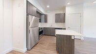 This contemporary 1-bedroom apartment in Midvale, Utah offers 630 square feet of thoughtfully designed living space. The open-concept floor plan seamlessly integrates the kitchen, living, and dining areas, creating a spacious feel. The modern kitchen is a standout feature, boasting sleek gray cabinetry, stainless steel appliances, and a stylish blue island that doubles as a breakfast bar. White subway tile backsplash and quartz countertops add a touch of elegance.

The generously sized 140 square foot bedroom provides ample space and features large windows that flood the room with natural light. A sliding glass door leads to a private balcony, offering outdoor views and fresh air. The bathroom is clean and contemporary, with a white tub-shower combination and modern fixtures.

Throughout the apartment, warm wood-look flooring adds warmth and complements the crisp white walls. Recessed lighting and high ceilings enhance the bright, airy ambiance. A hallway and closet provide additional storage space. Located at 8283 S Main Street in Midvale, this apartment combines modern design with practical living, perfect for those seeking a stylish and efficient urban lifestyle.