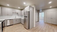 Located at 254 W 400 S in Salt Lake City, Utah, this single-floor unit offers a thoughtfully designed layout with modern finishes throughout. The kitchen is a standout feature, outfitted with gray flat-front cabinetry, white subway tile backsplash, white countertops, and a full suite of stainless steel appliances including a refrigerator, dishwasher, and range. Light wood-tone luxury vinyl plank flooring runs consistently through the entire unit, lending a clean and cohesive aesthetic. The bedrooms are bright and well-proportioned, with large windows fitted with horizontal blinds that allow ample natural light while maintaining privacy. One bedroom features a wide picture window with views to the exterior, while another includes a double-door closet for generous storage. The unit includes two bathrooms: one with a walk-in glass-enclosed shower and a white vanity with modern hardware, and another with a full soaking tub and shower combo, also finished with a white vanity. Recessed lighting throughout provides consistent, even illumination in every room. The overall design aesthetic is clean and contemporary, with a neutral color palette of whites and soft grays that creates a bright, move-in-ready living environment.