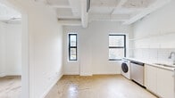 Located at 1039 W Lawrence Ave in Chicago's vibrant Uptown neighborhood, this single-floor unit blends industrial character with modern finishes. Polished concrete floors run throughout, complementing the exposed structural ceiling with visible ductwork and beam detailing that lend an authentic loft aesthetic to the space.

The open kitchen is thoughtfully appointed with crisp white cabinetry extending to the ceiling, a white subway tile backsplash, stainless steel appliances including a gas range, dishwasher, and full-size refrigerator, and a dedicated in-unit washer. The seamless flow from the kitchen into the main living area creates a flexible, open layout well-suited for both everyday living and entertaining.

A separate bedroom offers a generous closet with dual hanging rods and a window providing natural light and neighborhood views. Additional rooms include a bright secondary space with its own window, ideal as a home office or guest room. The bathroom features a walk-in shower with a handheld fixture, a clean white vanity with an integrated sink, and a black-framed window that allows natural light while maintaining privacy.

Black-framed windows throughout the unit frame views of the surrounding urban streetscape and bring in ample daylight. The overall aesthetic is clean, minimal, and functional — a well-designed urban retreat in one of Chicago's most dynamic and walkable neighborhoods.