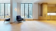 Located at 395 Square One Drive in the heart of Mississauga, this thoughtfully designed amenity space offers a sophisticated and functional environment across a single floor. The layout is divided into several distinct zones, each crafted to serve a specific purpose while maintaining a cohesive modern aesthetic throughout.

The lounge area is a standout feature, anchored by a generous sectional sofa in soft neutral tones, complemented by bold navy accent chairs and a sculptural green coffee table. Warm amber cove lighting recessed into a tray ceiling creates an inviting, intimate atmosphere, while curated artwork adds a refined finishing touch.

Adjacent to the lounge is a casual dining and collaboration zone, featuring light wood flooring, wall-mounted countertops, and vibrant teal pedestal seating. This area flows seamlessly into a glass-enclosed meeting room, visible through full-height glass partitions and outfitted with a conference table and colourful seating — ideal for private gatherings or focused work sessions.

Floor-to-ceiling windows throughout the space flood the interiors with natural light and frame sweeping views of the Mississauga skyline and the surrounding Square One district. Quieter nooks with individual seating and large glazed windows offer more contemplative settings. Light hardwood flooring, clean wall finishes, and built-in millwork unify the space, striking a balance between comfort and contemporary design.