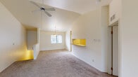 This single-story residence is designed with an open, airy layout that maximizes comfort and functionality throughout. The living area is a standout feature, boasting soaring vaulted ceilings and a ceiling fan that enhances airflow and the sense of spaciousness. Large sliding glass doors flood the room with natural light and provide access to an outdoor area, while neutral-toned carpet anchors the space with warmth. A pass-through counter connects the living area to the kitchen, creating a cohesive flow between spaces.

The kitchen is well-appointed with warm oak cabinetry offering generous upper and lower storage, light-toned countertops, hardwood flooring, and white appliances including a refrigerator, electric range, and dishwasher. A dedicated dining area adjacent to the kitchen is illuminated by a pendant light and a window overlooking the exterior.

The bedrooms are carpeted and feature natural light from recessed windows. One bedroom stands out with dual side-by-side closets, providing exceptional storage capacity. The two bathrooms serve the residence effectively — one includes a single-sink vanity with oak cabinetry and a tub/shower combination, while the second features a double-sink vanity and a separate walk-in shower, ideal for a primary suite.