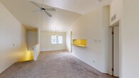 This single-story residence is designed with an open, airy layout that maximizes comfort and functionality throughout. The living area is a standout feature, boasting soaring vaulted ceilings and a ceiling fan that enhances airflow and the sense of spaciousness. Large sliding glass doors flood the room with natural light and provide access to an outdoor area, while neutral-toned carpet anchors the space with warmth. A pass-through counter connects the living area to the kitchen, creating a cohesive flow between spaces.

The kitchen is well-appointed with warm oak cabinetry offering generous upper and lower storage, light-toned countertops, hardwood flooring, and white appliances including a refrigerator, electric range, and dishwasher. A dedicated dining area adjacent to the kitchen is illuminated by a pendant light and a window overlooking the exterior.

The bedrooms are carpeted and feature natural light from recessed windows. One bedroom stands out with dual side-by-side closets, providing exceptional storage capacity. The two bathrooms serve the residence effectively — one includes a single-sink vanity with oak cabinetry and a tub/shower combination, while the second features a double-sink vanity and a separate walk-in shower, ideal for a primary suite.