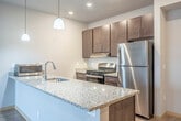 Located at 7944 Watts Rd in Madison, WI, this single-floor residence offers three bedrooms and two bathrooms with a thoughtfully designed layout. The open-concept living and kitchen area serves as the heart of the home, where light hardwood-style flooring extends throughout and large sliding glass doors with vertical blinds flood the space with natural light while providing outdoor views.

The kitchen is equipped with stainless steel appliances, including a gas range and full-size refrigerator, rich dark-toned cabinetry, and a granite-topped peninsula with pendant lighting overhead — ideal for both meal prep and casual dining. The living area flows seamlessly from the kitchen, creating an airy, connected feel.

The bedrooms are carpeted for comfort, each offering closet storage, including a built-in shelving system visible in one room. The primary bedroom is a generous size with its own sliding door access to the outdoors. Hallways connect the rooms efficiently, with recessed lighting guiding the way.

The two bathrooms feature tile flooring, clean white fixtures, and dark wood vanities. One bathroom is equipped with accessibility grab bars and a walk-in shower, while the second includes a full tub-shower combo. The overall aesthetic is clean, modern, and functional throughout.