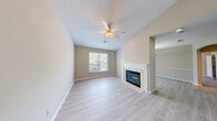 Located in Duluth, GA, this single-floor, one-bedroom, one-bathroom home offers a well-designed layout that maximizes comfort and functionality. The open-concept kitchen and living room serve as the heart of the home, where light hardwood-style flooring runs throughout the main area. The living room features vaulted ceilings, a ceiling fan, a large window framing views of lush greenery, and a tiled fireplace with a classic white mantel — creating a warm and inviting atmosphere. The kitchen is well-appointed with white cabinetry, granite countertops, stainless steel appliances including a refrigerator, electric range, and built-in microwave, alongside a peninsula with a sink that provides additional prep space and casual seating. A dedicated hallway leads to the spacious primary bedroom, which is carpeted and filled with natural light through a window overlooking trees. The bedroom provides access to a generous walk-in closet fitted with multi-level wire shelving. The full bathroom includes a tiled shower-tub combination, granite-topped vanity, and wood-style flooring. A dedicated laundry room houses a full-size top-loading washer and dryer with overhead shelving for added storage.