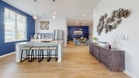 Located at 719 Lantern Walk Dr in Little River, SC, this thoughtfully designed community clubhouse offers a welcoming blend of coastal charm and modern sophistication. The single-floor space is anchored by a dramatic main lounge featuring soaring ceilings, warm light wood flooring, and a striking slatted wood ceiling element with integrated ambient lighting that draws the eye across the open layout. Curated coastal artwork and decorative accents appear throughout, reinforcing the waterside aesthetic.

The main gathering area is furnished with plush blue lounge chairs arranged around a central coffee table, alongside a dining area with upholstered chairs — ideal for both casual socializing and community events. A full kitchen with a granite-topped island, bar seating, stainless steel appliances, and decorative blue tile backsplash serves as a functional and stylish hub. Adjacent, a versatile lounge nook with a coastal theme provides additional seating.

Private offices, finished with bold blue accent walls and nautical artwork, offer quiet workspaces equipped with desks and carpeted flooring. Large windows flood the space with natural light and provide views of the surrounding community. A cable-rail mezzanine landing with woven pendant lights and floor-to-ceiling windows completes this well-appointed, detail-rich space.