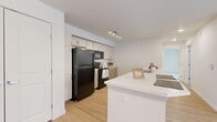 This single-floor, 2-bedroom, 3-bathroom unit offers a thoughtfully designed layout that maximizes functionality and comfort. The open-concept kitchen serves as the heart of the home, featuring light wood cabinetry, a large white quartz peninsula with a double stainless steel sink, and black appliances including a full-size refrigerator, electric range, and over-the-range microwave. Track lighting overhead keeps the space bright and practical. Light wood-look flooring flows throughout the kitchen and living areas, creating a clean, cohesive aesthetic with a neutral, modern palette.

The three bathrooms include units with full soaking tub and shower combinations, white tile surrounds, and a vanity bathroom featuring a wide white countertop, wood-tone cabinetry, and a large mirror. Each bathroom maintains a clean, minimal design. The bedrooms are carpeted for comfort and each is equipped with wall-mounted mini-split HVAC units for independent climate control, along with windows that bring in natural light. The generously sized primary bedroom connects to a dedicated walk-in closet outfitted with wire shelving and hanging rods. The second bedroom also features its own closet access. Overall, the unit presents a clean, contemporary living environment with practical finishes throughout.