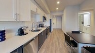 Located on the 8th floor at 2077 Haste Street in Berkeley, CA, this 900-square-foot apartment offers a well-designed 2-bedroom, 2-bathroom layout across a single floor. The galley-style kitchen is a standout feature, equipped with stainless steel appliances including an electric range, over-the-range microwave, refrigerator, and dishwasher. Two-tone cabinetry with white upper cabinets and dark lower cabinets pairs with a white quartz countertop and a classic subway tile backsplash, creating a clean, modern aesthetic. Light hardwood-style flooring flows through the kitchen, entrance, and hallway. The spacious primary bedroom measures 310 square feet and accommodates multiple beds and desks, making it well-suited for shared living. Both bedrooms feature large windows offering elevated city views and are finished with plush carpeting. The two bathrooms are distinctly appointed — one features a soaking tub and built-in shelving with wood-look flooring, while the other offers a single vanity with a large mirror and light tile flooring. A stacked washer and dryer unit is conveniently tucked within the unit. The overall ambiance is bright, clean, and contemporary throughout.