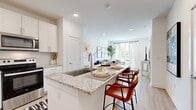 This thoughtfully designed single-floor residence showcases a bright, open-concept layout that seamlessly connects the kitchen, dining, and living areas. The kitchen is a standout feature, equipped with stainless steel appliances, crisp white shaker cabinetry, granite countertops, a subway tile backsplash, and a spacious island with a built-in sink and bar seating — ideal for both cooking and casual dining. Light hardwood-style flooring flows throughout the main living areas, enhancing the clean, contemporary aesthetic.

The living room is generously proportioned and filled with natural light from large sliding glass doors that open to a private balcony, offering views of the surrounding neighborhood. The bedroom features plush carpeting, ample natural light from windows with blinds, and a soft sage green accent wall that adds warmth and character to the space. A second bedroom provides additional comfort and flexibility.

The bathroom is finished with granite countertops, white cabinetry with chrome hardware, an undermount sink, and a large mirror, maintaining the cohesive, modern design found throughout the residence. Recessed lighting throughout the home ensures a well-lit, inviting ambiance in every room.