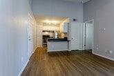 Located at 11315 Grandview Rd in Kansas City, MO, this single-story residence offers a well-organized layout with a thoughtful mix of materials and finishes throughout. The living area is a standout space, featuring soaring vaulted ceilings, a textured ceiling, and hardwood-style flooring that adds warmth and continuity. A fireplace with a tile surround serves as a focal point, flanked by built-in shelving for display or storage. Vertical blinds cover a sliding glass door that invites natural light into the room.

The kitchen is designed for functionality and openness, connected to the living area via a peninsula counter finished with a dark laminate surface. White cabinetry lines the walls, providing ample storage, while stainless steel appliances—including a refrigerator and range—add a modern touch. Track lighting illuminates the workspace efficiently.

The bedroom areas feature plush carpeting and neutral wall tones, creating a calm and comfortable atmosphere. Closet access and proximity to the bathroom enhance the practicality of the private quarters. The bathroom includes a full-size soaking tub with a clean white surround. Throughout the unit, the neutral gray palette and consistent finishes contribute to a cohesive, move-in-ready aesthetic.