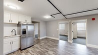 Located at 101 Cedar St in Providence, Rhode Island, this thoughtfully updated single-floor unit offers a clean, modern aesthetic with a neutral gray and white color palette throughout. The open kitchen is a standout feature, outfitted with crisp white shaker cabinets, a full suite of stainless steel appliances including a French door refrigerator, electric range, built-in microwave, and dishwasher, all complemented by durable wood-look luxury vinyl plank flooring. Exposed black pipe detailing in the main living area adds an industrial accent to the otherwise clean design. Multiple bedrooms are finished with plush gray carpet, baseboard heating, and windows with blinds that allow for natural light and ventilation. One carpeted bedroom also features a wall-mounted air conditioning unit and convenient closet with sliding doors. The bathroom is efficiently designed, incorporating a full tub and shower combo, a vanity with sink, and a stacked in-unit GE washer and dryer — a practical and space-conscious amenity. Throughout the unit, wide baseboards, neutral wall tones, and consistent flooring choices create a cohesive and well-maintained living environment.