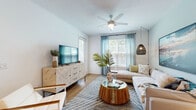 Located at 1124 Shoreview Cir in Casselberry, Florida, this thoughtfully designed single-floor residence offers a cohesive coastal aesthetic throughout its well-appointed spaces. The living room serves as the heart of the home, featuring light hardwood-style flooring, crisp white walls, and an abundance of natural light streaming through multiple windows dressed in soft aqua curtains and wood blinds. A ceiling fan overhead, woven pendant lighting, and a warm, neutral color palette create an inviting and airy atmosphere.

The kitchen is a functional standout, showcasing a two-tone cabinetry design with white upper cabinets and gray lower cabinets, complemented by a light gray subway tile backsplash, white quartz countertops, and a full suite of stainless steel appliances including a range, microwave, dishwasher, and refrigerator.

The two bedrooms offer comfortable retreats, each with natural light from well-positioned windows, ceiling fans, and light hardwood-style flooring. The primary bedroom features a soft sage accent wall, adding a calming, distinctive touch.

The bathroom is finished with gray shaker-style cabinetry, a dual-sink vanity with white countertops, a large framed mirror, and light blue walls that reinforce the home's coastal character. Throughout, the space balances modern finishes with relaxed, livable warmth.