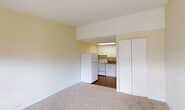 Located at 10535 SW 216th St in Cutler Bay, Florida, this compact single-floor unit offers an efficient and functional layout designed to maximize every square foot. The living area features neutral-toned carpeting, warm cream-colored walls, and a textured ceiling that adds subtle character. A large window with horizontal blinds fills the room with natural light while offering a pleasant view of the surrounding greenery and community grounds. A wall-mounted HVAC unit ensures year-round comfort.

The kitchen is neatly defined within the open layout, featuring white cabinetry, a white refrigerator, an electric range, and a sink — all under overhead lighting that keeps the space bright and practical. A closet adjacent to the kitchen provides convenient storage. The bathroom includes a clean, white tub and shower combination with textured walls.

Outside, a semi-private patio area is enclosed by a wooden fence, decorated with red mulch landscaping and stepping stone pavers, offering a quiet outdoor retreat. Mature trees and well-maintained grounds surround the exterior, contributing to a serene residential atmosphere. This unit presents a straightforward, no-frills living space well-suited for those seeking practicality in a peaceful South Florida community.