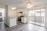 Located at 801 South Lyon Street in Santa Ana, CA, this one-bedroom, two-bathroom residence offers a thoughtfully arranged single-level floor plan designed to maximize comfort and functionality. The open-concept living area features light gray wood-look laminate flooring, a textured ceiling, a ceiling fan, and a wall-mounted air conditioning unit. Vertical blinds frame a large window that draws in generous natural light, while a sliding glass door provides direct access to an outdoor area. The galley-style kitchen is well-appointed with white cabinetry, granite-look countertops, a stainless steel gas range, a double-basin sink, and wood-look flooring that flows seamlessly throughout the main living spaces. A peninsula counter separates the kitchen from the living area, adding both storage and prep space. The spacious bedroom is carpeted and features a large closet with sliding doors and a window with vertical blinds. Two full bathrooms serve the unit, each finished in clean white tones — one featuring a full bathtub and shower combination with chrome fixtures. Additional bathroom vanities include wide mirrors, bright vanity lighting, and white cabinetry with granite-look countertops, completing this well-maintained and move-in ready residence.