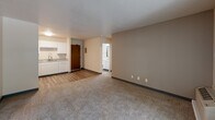 Located at 400 Second Ave in Des Moines, Iowa, this single-floor unit offers a straightforward, functional layout designed for comfortable everyday living. The open-concept living area serves as the central hub of the space, featuring neutral beige walls, wall-to-wall carpeting, and a textured ceiling. The area flows directly into the kitchen, which is finished with wood-look vinyl flooring, white cabinetry, speckled granite-style countertops, a double stainless steel sink with a modern pull-down faucet, and a white electric range. Ample upper and lower cabinet storage provides practical utility throughout the kitchen.

A separate bedroom offers a quiet retreat with generous carpeted floor space, neutral walls, and a window that frames views of surrounding greenery, allowing natural light to fill the room. A wall-mounted HVAC unit provides climate control directly within the space.

The bathroom is cleanly appointed with wood-look vinyl flooring, a white vanity with a speckled countertop, a toilet, and a full tub and shower combination with a curved curtain rod and grab bar. The overall palette throughout the unit is light and neutral, contributing to a clean, move-in-ready ambiance.