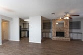 Located at 509 Delmar St in Midland, Texas, this single-story home offers a practical and comfortable layout with a variety of notable interior features. The entry foyer welcomes you with tile flooring and sidelight windows that bring in natural light, transitioning into a spacious living area finished with warm wood-look flooring. The living room serves as the heart of the home, anchored by a full-height brick fireplace flanked by built-in shelving and cabinetry on both sides — an ideal setup for storage and display. A ceiling fan overhead adds comfort to the space. The kitchen is positioned adjacent to the living area and features white cabinetry, dark speckled countertops, a black electric range with overhead ventilation hood, and a black refrigerator, providing a clean and functional cooking space. The bedroom is generously sized, fitted with plush carpet, a ceiling fan, and a window that allows natural light to filter in. The bathroom includes a vanity with cabinetry, a large mirror, and wood-look flooring consistent with the rest of the home. A textured ceiling is present throughout, adding a classic residential character. Overall, the home presents a cohesive and functional single-floor living environment.