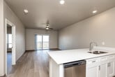 Located on Jasper Ave NW in Tiffin, Iowa, this one-bedroom, one-bathroom unit offers a well-designed, single-floor layout with a clean, modern aesthetic throughout. Light wood-tone flooring flows seamlessly across the entire unit, complementing the neutral warm-beige and soft-gray wall tones.

The open-concept living, dining, and kitchen area forms the heart of the unit. The kitchen is equipped with white shaker-style cabinetry, quartz countertops, stainless steel appliances including a refrigerator, range, and over-the-range microwave, and a large peninsula with an undermount sink — ideal for both cooking and casual dining. Recessed lighting brightens the kitchen, while the adjoining living area features a ceiling fan and a sliding glass door that opens to a private balcony with open outdoor views.

The bedroom is a comfortable size, featuring light wood flooring, a ceiling fan, a large window with scenic views of the surrounding landscape, and access to a spacious walk-in closet with wire shelving on three sides. Two additional closets provide generous storage throughout the unit.

The full bathroom includes a white vanity with quartz countertops, a full soaking tub with shower, and light wood flooring. A dedicated laundry area houses a stacked GE washer and dryer alongside a water heater, keeping all utilities efficiently contained within the unit.