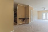 Located at 5505 Oxford Trace Way in Virginia Beach, Virginia, this single-floor home offers a thoughtfully designed layout with a variety of comfortable living spaces. The kitchen is a functional galley-style space featuring rich dark wood cabinetry, dark granite-style countertops, hardwood-style flooring, and a full suite of black appliances including a gas range, built-in microwave, refrigerator, and dishwasher. A door from the kitchen leads to an adjacent pantry or utility area, adding practical storage. The living areas are finished with plush neutral carpeting, warm beige walls, and elegant crown molding, creating a cohesive and inviting atmosphere. Track lighting accents the main living space, while a ceiling fan adds comfort to the primary bedroom, which also features vaulted ceilings and direct access to a private bathroom and walk-in closet. Additional bedrooms are generously sized, each with ceiling fans, plush carpeting, ample closet space, and windows that bring in natural light. The full bathroom is cleanly appointed with tile flooring, a tub-shower combination with white tile surround, and a vanity with storage. Overall, the home presents a neutral, move-in-ready aesthetic with consistent finishes throughout.