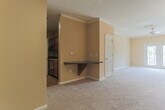 Located at 5505 Oxford Trace Way in Virginia Beach, Virginia, this single-floor home offers a thoughtfully designed layout with a variety of comfortable living spaces. The kitchen is a functional galley-style space featuring rich dark wood cabinetry, dark granite-style countertops, hardwood-style flooring, and a full suite of black appliances including a gas range, built-in microwave, refrigerator, and dishwasher. A door from the kitchen leads to an adjacent pantry or utility area, adding practical storage. The living areas are finished with plush neutral carpeting, warm beige walls, and elegant crown molding, creating a cohesive and inviting atmosphere. Track lighting accents the main living space, while a ceiling fan adds comfort to the primary bedroom, which also features vaulted ceilings and direct access to a private bathroom and walk-in closet. Additional bedrooms are generously sized, each with ceiling fans, plush carpeting, ample closet space, and windows that bring in natural light. The full bathroom is cleanly appointed with tile flooring, a tub-shower combination with white tile surround, and a vanity with storage. Overall, the home presents a neutral, move-in-ready aesthetic with consistent finishes throughout.