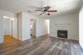 Located in the Plantation community of Olive Branch, Mississippi, this single-floor residence offers a well-organized layout with a clean, neutral aesthetic throughout. The living room serves as the heart of the home, showcasing a classic wood-burning fireplace with a white mantel, wood-look luxury vinyl flooring, a ceiling fan, and a sliding glass door that fills the space with natural light. Adjacent to the living room, a dedicated dining area features warm wood-look flooring and an elegant chandelier, creating an inviting setting for meals. The galley-style kitchen is efficiently designed with white cabinetry, white appliances including an electric range and built-in microwave, light countertops, and easy-care wood-look flooring. A bi-fold door leads to a laundry area for added convenience. The bedrooms are carpeted for comfort and each include ceiling fans with light fixtures. At least one bedroom benefits from a walk-in closet and a window with natural light. Two full bathrooms are finished with wood-look flooring and include tub-shower combinations with chrome fixtures. The space maintains a bright, neutral palette with white walls and trim, offering a clean canvas throughout.
