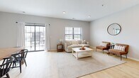 This well-appointed three-story home offers four bedrooms and three bathrooms, thoughtfully laid out across its multiple levels. The entry level provides a welcoming foyer with light wood flooring, high ceilings, and windows that invite natural light into the space. A staircase connects the floors with ease and continuity of design.

The main floor serves as the heart of the home, housing a combined living, dining, and kitchen area. The living room features vaulted ceilings, light wood flooring, and access to a private balcony through a sliding glass door — ideal for bringing in outdoor light and views. The dining area showcases a herringbone-patterned wood table set beneath soft, neutral-toned walls, while the kitchen completes this open, social layout.

Bathrooms across the home are clean and functional, with one featuring a walk-in shower, and another a sleek pedestal sink. A dedicated closet with wire shelving provides additional storage. The primary bedroom is a generous, well-lit retreat with a large window, light wood floors, and ample space for rest. Additional bedrooms are versatile, accommodating both sleeping and workspace needs. Throughout, a consistent palette of soft grays, warm wood tones, and recessed lighting creates a cohesive, modern aesthetic.