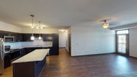 Located at 23580 E Portland Way in Aurora, Colorado, this single-floor residence offers a well-designed open-concept layout that seamlessly connects the kitchen and living areas. The kitchen is a standout feature, equipped with dark espresso cabinetry, granite countertops, stainless steel appliances including a refrigerator, range, microwave, and dishwasher, and a large center island ideal for meal prep or casual dining. Pendant lighting and a built-in wine rack add refined touches to the space. Rich, wood-tone flooring runs throughout the main living and kitchen areas, creating a warm and cohesive aesthetic. The spacious living area benefits from natural light and includes a ceiling fan for added comfort. The bedrooms are carpeted for warmth and comfort, with windows offering views of the surrounding neighborhood. The primary bedroom includes access to closets and a private bathroom area. The bathrooms throughout feature granite-topped dark vanities with large mirrors and modern fixtures, maintaining a consistent design language. The neutral color palette and clean lines throughout the space provide a versatile backdrop suited to a variety of interior styles.