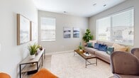 This two-story home is designed with a clean, contemporary aesthetic throughout, making use of neutral tones, light-filled rooms, and practical finishes. The main level showcases a bright living room with light hardwood-style flooring, large windows that invite natural light, and views of the surrounding neighborhood. The modern kitchen is well-equipped with crisp white shaker cabinetry, white quartz countertops, a subway tile backsplash, and stainless steel appliances including a range, over-the-range microwave, and a French door refrigerator with an ice and water dispenser.

The upper level, accessed by a carpeted staircase with a sleek handrail, contains the bedrooms and additional living spaces. The primary bedroom is spacious and comfortable, featuring plush carpeting, a large window with neighborhood views, and access to a secondary room. An additional bedroom offers similar finishes with a ceiling fan and ample natural light. A dedicated office or flex room provides a quiet retreat with a large window and carpet flooring. The bathroom features a white undermount sink, quartz vanity, a large mirror, and a shower-tub combination with built-in shelving, maintaining the home's clean and functional design throughout.