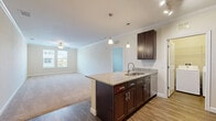 Located in Orlando, FL, this single-story, 2-bedroom, 2-bathroom home offers a well-designed layout with a seamless blend of comfort and modern finishes. The heart of the home is an open-concept living, dining, and kitchen area, where rich dark-cabinetry kitchen features granite countertops, a center island with a built-in sink, stainless steel appliances including a refrigerator and range, and stylish pendant lighting. Wood-look flooring runs throughout the kitchen and living areas, transitioning to plush carpet in the bedrooms and living room. Crown molding adds a refined architectural detail throughout the common areas. The spacious primary bedroom includes a ceiling fan, generous closet space with wire shelving, and direct access to its own bathroom. The second bedroom features carpet flooring, a ceiling fan, and a bright window with outdoor views. Both bathrooms are finished with dark wood vanities topped with granite, wood-look tile flooring, and tub/shower combinations clad in large-format marble-style tile with decorative accent borders. Additional conveniences include a dedicated laundry area, utility room, and ample hallway storage, rounding out this thoughtfully arranged home.