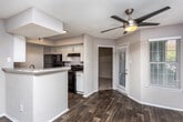 Located at 1955 Bells Ferry Rd in Marietta, Georgia, this single-floor residence offers a well-designed layout that balances comfort and functionality. The open-concept living area is a highlight of the home, featuring rich dark wood-style flooring, a ceiling fan, and multiple windows dressed with white blinds that invite generous natural light. A tile-surround fireplace with a classic white mantel serves as the focal point of the main living space, flanked by windows that offer views of the surrounding greenery.

The galley-style kitchen is efficiently arranged with white cabinetry, granite-style countertops, a double sink, and black appliances including a gas range, refrigerator, and dishwasher. A breakfast bar peninsula connects the kitchen to the living area, enhancing the open flow of the space.

The bedrooms are carpeted for comfort, with one bedroom featuring direct access to a bathroom and a walk-in closet with built-in shelving. The bathroom includes a full soaking tub with tile surround and dark wood-style flooring. Additional rooms provide flexibility for various uses. A dedicated entryway with wood-style flooring completes this practical and well-appointed home.