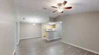 This single-story residence in Mobile, Alabama presents a well-organized floor plan designed for comfortable everyday living. The open-concept living and dining area features wood-style plank flooring, a ceiling fan with light fixture, and vaulted ceiling details that lend a sense of spaciousness. A pendant light marks the dining space, while a peninsula counter connects the living area to the kitchen, providing a natural pass-through for entertaining.

The galley-style kitchen is equipped with light wood cabinetry, laminate countertops, a double sink, and white appliances including a range, refrigerator, and built-in microwave. Wood-style flooring continues throughout, maintaining a cohesive aesthetic.

A dedicated living area features French doors that open to the outdoors, inviting natural light and exterior views. Both bedrooms are carpeted and include ceiling fans, natural light from windows, and closet storage. The primary bedroom includes a sizable closet with paneled doors.

Each of the two full bathrooms features a tub-shower combination with tiled surround, wood-look flooring, and vanity cabinetry. A central hallway connects the private bedroom wing to the main living spaces, completing the functional single-floor layout.
