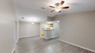 This single-story residence in Mobile, Alabama presents a well-organized floor plan designed for comfortable everyday living. The open-concept living and dining area features wood-style plank flooring, a ceiling fan with light fixture, and vaulted ceiling details that lend a sense of spaciousness. A pendant light marks the dining space, while a peninsula counter connects the living area to the kitchen, providing a natural pass-through for entertaining.

The galley-style kitchen is equipped with light wood cabinetry, laminate countertops, a double sink, and white appliances including a range, refrigerator, and built-in microwave. Wood-style flooring continues throughout, maintaining a cohesive aesthetic.

A dedicated living area features French doors that open to the outdoors, inviting natural light and exterior views. Both bedrooms are carpeted and include ceiling fans, natural light from windows, and closet storage. The primary bedroom includes a sizable closet with paneled doors.

Each of the two full bathrooms features a tub-shower combination with tiled surround, wood-look flooring, and vanity cabinetry. A central hallway connects the private bedroom wing to the main living spaces, completing the functional single-floor layout.