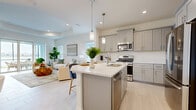 Located at 2547 Beachcomber Inlet Loop in Bradenton, FL, this well-appointed single-story home offers three bedrooms, three bathrooms, a dedicated office, and a thoughtfully designed open-concept layout. Light-toned tile flooring runs throughout the main living areas, complementing the bright, neutral color palette that defines the interior aesthetic.

The heart of the home is the combined kitchen, dining, and living area. The kitchen features gray shaker-style cabinetry, stainless steel appliances, a white quartz-topped island with bar seating, and pendant lighting — all flowing seamlessly into the living room, which is bathed in natural light from multiple windows. A separate dining room provides an intimate space for formal meals.

The generously sized primary bedroom offers plush carpeting, a ceiling fan, and a large window with outdoor views. The office is a bright, multi-windowed room ideal for working from home. Three full bathrooms are finished in clean, neutral tones with tile flooring. A dedicated laundry room with full-size washer and dryer adds everyday convenience.

Two hallways connect the home's rooms efficiently, and a closet provides additional storage. The overall ambiance is airy, modern, and functional — a comfortable Florida retreat designed for single-floor living.