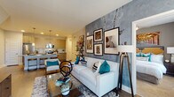 This single-floor residence showcases a thoughtfully designed open-concept layout that seamlessly connects the living, dining, and kitchen areas. The living room is a standout space, anchored by a striking textured accent wall with an industrial, concrete-like finish that serves as a backdrop for a curated gallery of framed artwork. Large windows allow generous natural light to fill the room, complementing the warm hardwood-style flooring that extends throughout the main areas.

The kitchen is well-appointed with wood-tone cabinetry extending to the ceiling, granite countertops, a full suite of stainless steel appliances, a subway tile backsplash, and a large island with seating — ideal for casual dining. Pendant lighting adds a refined touch overhead.

Both bedrooms are comfortably scaled, featuring plush carpeting, large windows with ample natural light, and easy access to their respective bathrooms. Each bathroom is finished with wood-tone vanities, granite countertops, hardwood-style flooring, and a tub-shower combination. One bedroom includes a walk-in closet area with built-in shelving. The overall ambiance is modern and cohesive, with neutral tones and contemporary finishes creating a polished, move-in-ready feel throughout.
