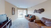 Located at 5105 S Rolling Green Ave in Sioux Falls, South Dakota, this single-floor unit offers a practical and comfortable layout. The living area is finished with soft carpeting and neutral walls, creating a welcoming atmosphere. A large sliding glass door draws in natural light and provides a view of the surrounding exterior. The space accommodates generous seating and features decorative wall accents that add character to the room.

The kitchen is efficiently designed with light wood cabinetry extending to the ceiling, offering ample storage. White appliances, including a coil-burner range, over-the-range microwave, and dishwasher, are neatly integrated alongside clean white countertops. Wood-look flooring runs through this area, providing a clean contrast to the surrounding cabinetry.

The bedroom is a comfortably sized retreat with plush carpeting, a window that allows natural light to filter in, and adequate space for full bedroom furniture. A textured ceiling and flush-mount light fixture complete the room.

The bathroom features light wood cabinetry beneath a wide white countertop with an undermount sink, a large mirror with overhead lighting, and wood-look flooring, maintaining a cohesive and clean aesthetic throughout the unit.