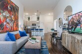Located on Atlanta Student Movement Boulevard SW in Atlanta, GA, this single-floor residence showcases a thoughtfully designed open-concept layout that seamlessly connects the kitchen, dining, and living areas. The kitchen is a standout, featuring granite countertops, a large center island with seating, stainless steel appliances, and a two-tone cabinet scheme of dark wood lower cabinets and light upper cabinets. Decorative upper wall panels add an artistic touch above the cabinetry. Rich hardwood flooring flows throughout the main living spaces, complemented by soaring ceilings that enhance the sense of openness. The living area is bright and airy, with tall windows that invite generous natural light. Two well-sized bedrooms offer plush carpeting, elevated ceilings, and large windows with ample natural light. Both bathrooms are finished with granite-topped dark wood vanities, tub-shower combinations, and hardwood-style flooring. The consistent use of granite countertops and dark wood cabinetry across the kitchen and bathrooms creates a cohesive, upscale aesthetic throughout the residence.