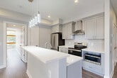 Located at 3549 Georgia Ave NW in Washington, DC, this single-floor unit offers a thoughtfully designed layout comprising a living room, kitchen, hallway, and two full bathrooms. The kitchen is a standout feature, showcasing gray shaker-style cabinetry, quartz countertops, a center island with an undermount sink, and a herringbone-patterned tile backsplash. Stainless steel appliances, including a French door refrigerator and a double oven range, are complemented by a stainless steel range hood and elegant pendant lighting above the island. Wood-look luxury vinyl plank flooring flows throughout, adding warmth and continuity. The two bathrooms are finished to a high standard, each featuring marble-look tile flooring, tub-shower combinations with full tile surrounds, built-in niche shelving, and gray vanities with brushed nickel or gold hardware. The living area is bright and open with neutral gray walls and abundant natural light. The hallway connects the spaces efficiently, maintaining a clean, modern aesthetic throughout. The overall design palette — soft grays, whites, and natural wood tones — creates a cohesive, contemporary ambiance well-suited for urban living in the vibrant Georgia Avenue corridor.