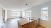 Located at 1 East Main in Bay Shore, NY, this single-floor residence offers a thoughtfully designed open-concept layout filled with natural light from multiple large windows overlooking the vibrant streetscape. The expansive living and dining area features warm wood-look flooring and recessed lighting, creating a bright and welcoming atmosphere. A central kitchen island with a sleek quartz countertop and undermount sink serves as the focal point of the space, seamlessly connecting the kitchen to the living area. The kitchen is well-appointed with warm wood cabinetry, stainless steel appliances including a refrigerator, electric range, microwave, and dishwasher, along with ample counter and storage space. Two generously sized bedrooms each offer wood-look flooring and windows with views of the surrounding neighborhood. The bathrooms are finished with clean, modern details — one featuring full-height neutral tile surrounding a soaking tub and shower combination, and another with a wood-toned vanity, light tile flooring, and a wall-mounted mirror. Clean white walls and contemporary finishes throughout lend the space a cohesive, move-in-ready aesthetic ideally suited for urban living in downtown Bay Shore.