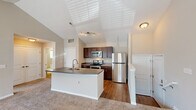 Located at 2000 Burgess Dr in Uniontown, OH, this one-bedroom, one-bathroom residence offers a thoughtfully designed single-floor layout. The open-concept living and kitchen area serves as the heart of the home, highlighted by vaulted ceilings that lend a sense of spaciousness. The kitchen is well-appointed with rich dark wood cabinetry, stainless steel appliances including a refrigerator, electric range, and over-the-range microwave, and a central island with a sink and gray countertops. Light hardwood-style flooring runs through the kitchen, transitioning to plush carpeting in the living area. The living room is bright and inviting, featuring French doors that open to the exterior and a large window that draws in natural light. The bedroom offers a comfortable layout with multiple windows providing ample natural light and direct access to a spacious walk-in closet equipped with wire shelving and hanging rods along three walls. The bathroom features wood-style flooring, a tub-shower combination, a vanity with matching dark wood cabinetry and gray countertop, and a window for natural ventilation. Neutral tones throughout create a clean, move-in-ready atmosphere.