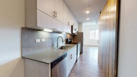 Located at 1000 N Grant St in Denver's Capitol Hill neighborhood, this single-floor residence showcases a contemporary design with clean lines and modern finishes throughout. The open-concept layout connects the living area to the kitchen, creating a sense of spaciousness and easy flow between spaces.

The kitchen is a standout feature, offering a galley-style configuration with floor-to-ceiling cabinetry in a light wood finish, a tile backsplash, quartz countertops, a deep stainless steel sink, and a full suite of stainless steel appliances including a refrigerator, range, microwave, and dishwasher. A warm natural wood accent frames the kitchen entry, adding an organic touch to the otherwise modern palette.

The living area is bright and versatile, featuring wood-look flooring, recessed lighting, and a large window that brings in natural light and views of the surrounding neighborhood. The open wall space provides flexibility for various furniture arrangements.

The bathroom is finished in crisp white tile with a full soaking tub and shower combination, accented by a vertical strip of gray mosaic tile and brushed nickel fixtures. A dark-framed door adds a modern contrast to the bright, clean interior. Throughout the unit, wood-look flooring, neutral walls, and thoughtful detailing come together to create a cohesive, move-in-ready living environment.