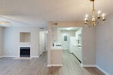 Located at 248 Debuys Rd in Biloxi, Mississippi, this single-story, one-bedroom, one-bathroom residence offers a well-organized layout across a compact but functional floor plan. The combined living and dining area serves as the heart of the home, featuring light wood-tone luxury vinyl plank flooring, a ceiling fan with light fixture, a decorative fireplace with tile surround, and a built-in wall niche. French doors lead out to a private patio, filling the space with natural light. An elegant chandelier marks the transition into the dining area. The galley-style kitchen is outfitted with white cabinetry, light stone-patterned countertops, a gas range with over-the-range microwave, a dishwasher, refrigerator, and a stainless steel sink — all set over matching LVP flooring. A pantry and dedicated laundry area add to the kitchen's storage and utility. The bedroom is a comfortable size, finished with plush carpet, a ceiling fan, and a window with blinds for natural light and privacy. Multiple closets throughout provide generous storage. The bathroom features a vanity with stone-patterned countertop, a large mirror with overhead lighting, and LVP flooring. A textured ceiling is consistent throughout the unit.