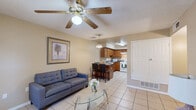 Located at 4980 Sean Haggerty Dr in El Paso, TX, this single-story, 3-bedroom, 2-bathroom home offers a practical and comfortable layout. Light ceramic tile flooring runs throughout, creating a cohesive and easy-to-maintain interior. The open living room flows directly into the kitchen, forming a combined common area anchored by a ceiling fan with light fixture. The kitchen features warm-toned wood cabinetry, dark granite-style countertops, a peninsula breakfast bar with seating, a white gas range, dishwasher, and ample cabinet storage. Each of the three bedrooms is equipped with a ceiling fan and closet; the bedrooms maintain a neutral, warm palette with tiled floors and natural light from windows. Four closets total provide generous storage throughout the home. Both bathrooms include wood-cabinet vanities with mirrors, tile flooring, and tub/shower combinations. A dedicated in-unit laundry area accommodates a full-size side-by-side washer and dryer with an overhead storage shelf above. A hallway connects the private sleeping quarters to the main living areas, completing a well-organized, single-level floor plan designed for functional everyday living.