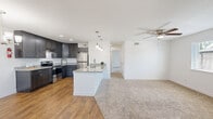 This single-floor residence offers two bedrooms and two bathrooms within a thoughtfully designed open-concept layout. The kitchen and living area flow seamlessly together, creating a functional and welcoming shared space. The kitchen is outfitted with dark espresso cabinetry, granite countertops, stainless steel appliances including a refrigerator and range, and a central island with a built-in sink and pendant lighting above. Recessed lighting and wood-look flooring complete the kitchen's modern aesthetic.

The living area transitions smoothly from the kitchen via a change in flooring to plush, neutral-toned carpet. A ceiling fan provides comfort overhead, and a window allows natural light into the space. The open sightlines between the kitchen and living room enhance the sense of spaciousness throughout.

The primary bedroom is a comfortable size, featuring carpet flooring, a ceiling fan with a window for natural light, and direct access to the hallway. The second bedroom offers carpet flooring, neutral white walls, and a large double bi-fold closet, providing ample storage. Both bathrooms are clean and functional, with one featuring a full tub-shower combination finished in crisp white surrounds with built-in shelving.
