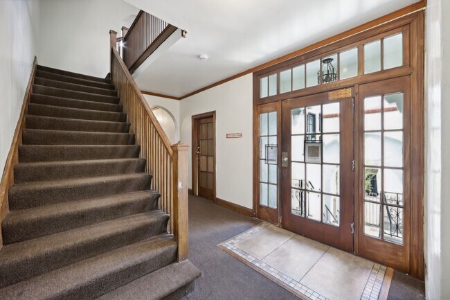 Hallway with a wooden staircase and banister, a wooden door with glass window - 2410 Dwight Way